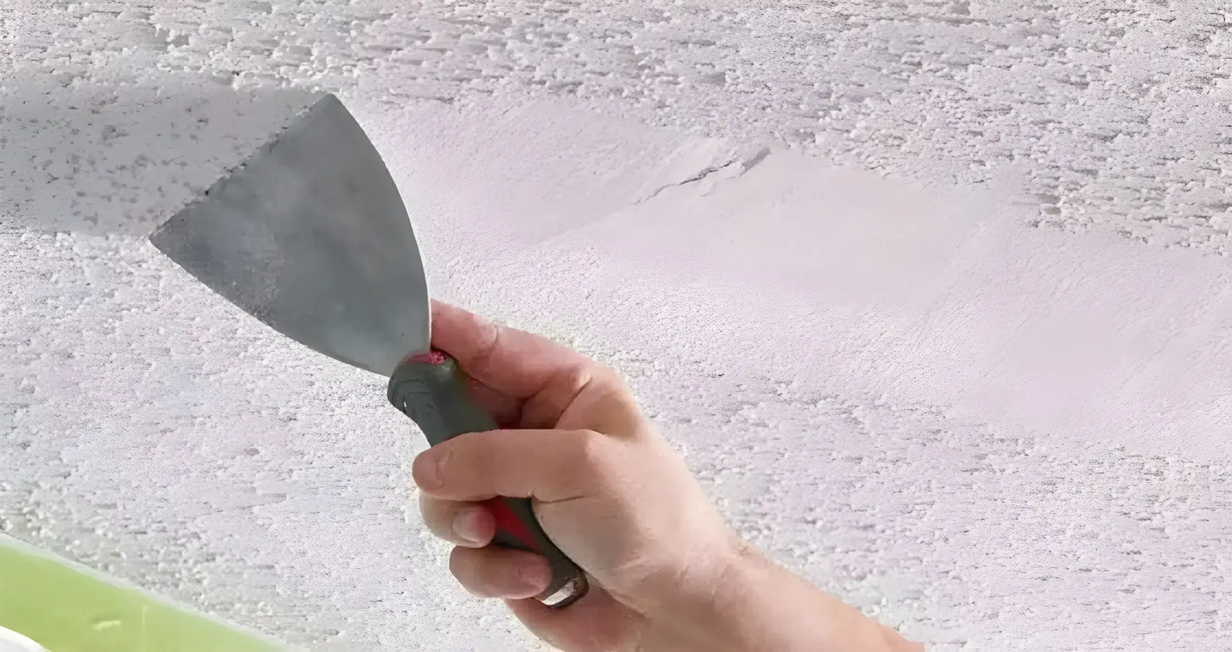 Los Pintores en Granada eliminando el gotelé con espátula para dejar la pared lisa